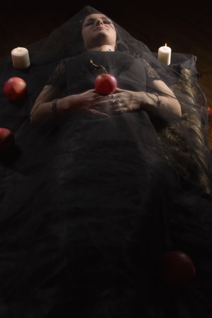 Gothic Snow White. Woman with poisoned apple lies in a tomb