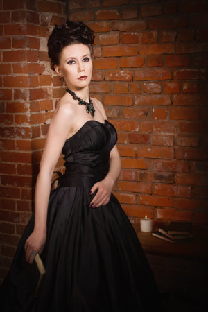 Sensual gothic woman in a long gorgeous black dress at dark interiorの写真素材