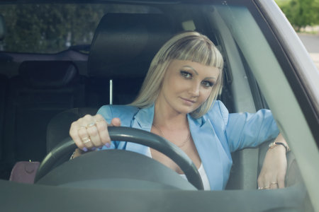 Young confident businesswoman driving car. City concept