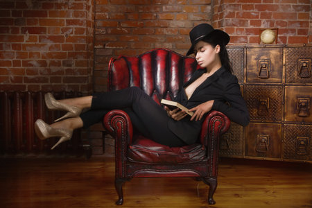 Elegant fashionable woman wearing black suit and hat in a vintage interior. Noir film styleの写真素材