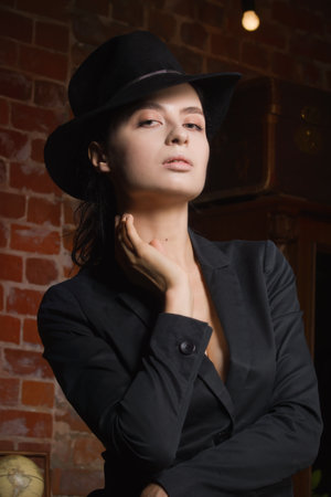 Elegant fashionable woman wearing black suit and hat in a vintage interior. Noir film styleの写真素材