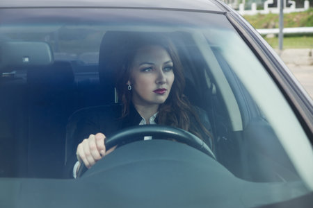Young confident businesswoman driving car. City concept