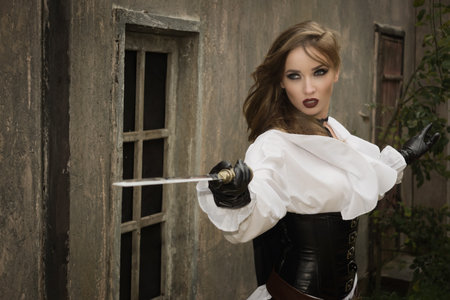 Fashion portrait of sexy woman in pirate style holding swordの写真素材