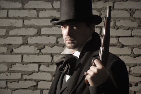 Victorian style man in a black suit and with old gun