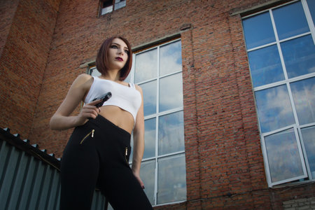 Noir film style woman in a black suit posing with a gunの写真素材