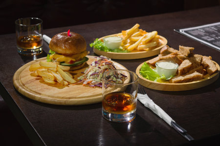 Delicious Pub Food. Burgers And Glasses Of Whiskey On Wooden Platesの写真素材