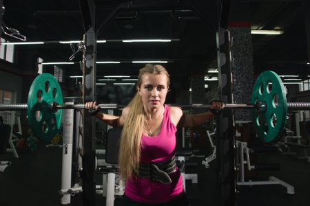 Beautiful girl exercising squatting with barbell