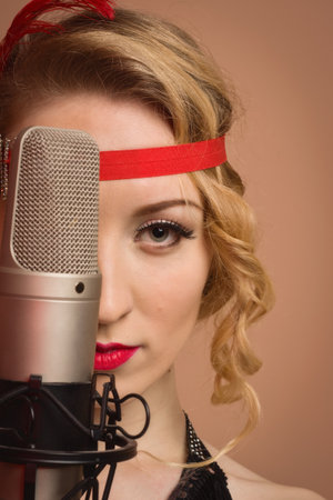 Gorgeous vintage 1920s lady with microphone in a black dress with headbandの写真素材