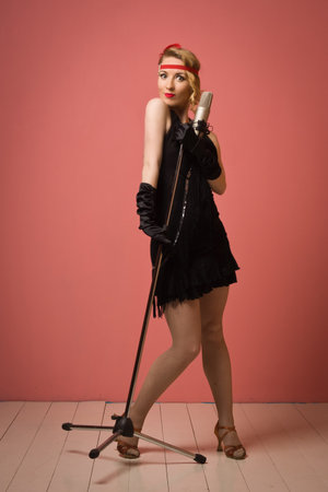 Gorgeous vintage 1920s lady with microphone in a black dress with headband