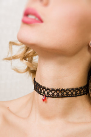 Beautiful woman showing her neck with a choker jewelry on itの写真素材