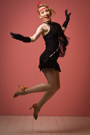 Gorgeous vintage 1920s lady dancing the charleston in a black dress with headbandの写真素材
