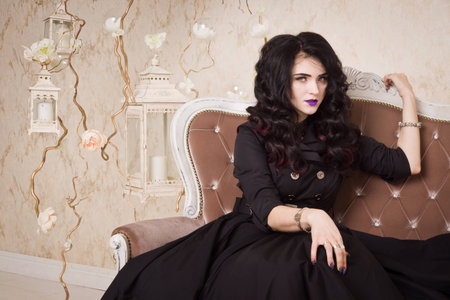 Sensual gothic woman in a long gorgeous black dress at white interiorの写真素材