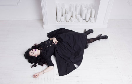 Sensual gothic woman in a long gorgeous black dress at white interiorの写真素材