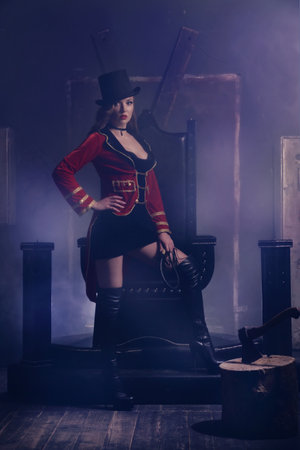 Beautiful woman trainer in a circus suit and a hat sits on the throne