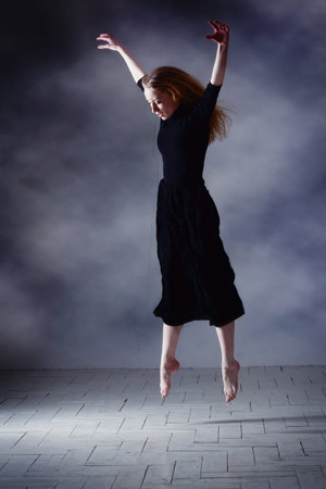 Young modern ballet dancer posing on dark backgroundの写真素材