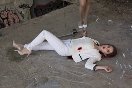 Two women are fighting at swords. One of them is defeated, the second wraps her body in polyethylene