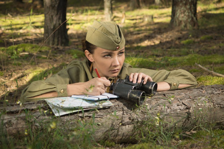 Woman in uniform of the Red Army of the Second World War. She watches through binoculars and scouts.