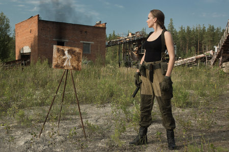 Girl in uniform with a gun in an abandoned factory