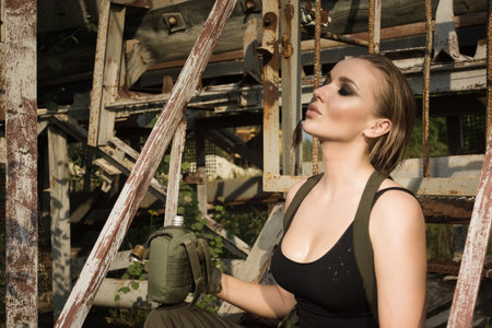 The girl in uniform eagerly drinks water from the flaskの写真素材