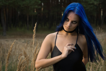 Beautiful woman with dark blue hair dressed in black dress in the magic forest. Gothic style. 