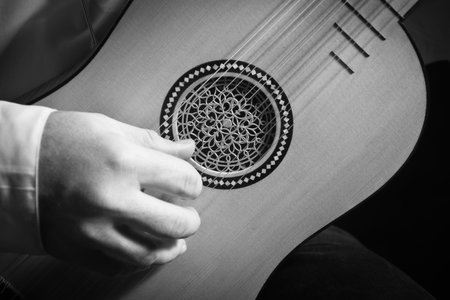 Man playing spanish renaissance instrument vihuela de mano over black の写真素材