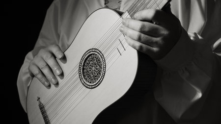 Man playing spanish renaissance instrument vihuela de mano over black の写真素材