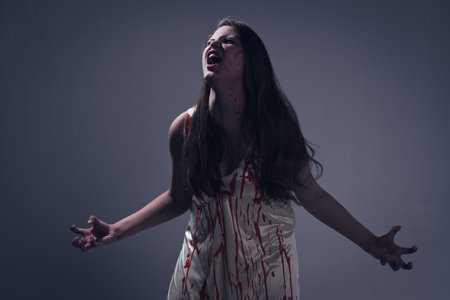 Horror film. A girl in a bloody dress screams in pain
の写真素材