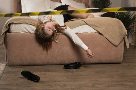Strangled beautiful business woman in a bedroom. Simulation of the crime scene.