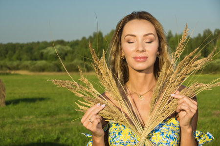 beautiful young girl with wheat ears in a summer fieldの写真素材