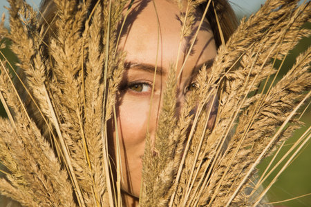 beautiful young girl with wheat ears in a summer fieldの写真素材