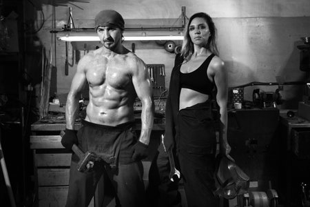 Brutal man and a beautiful woman in a metalwork shop.の写真素材