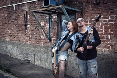 Girl and guy punks on a city street play on guitarsの写真素材