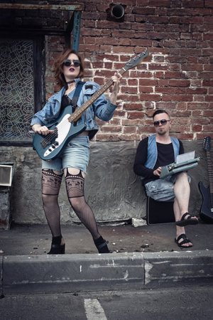 Girl and guy punks on a city street play on guitarsの写真素材