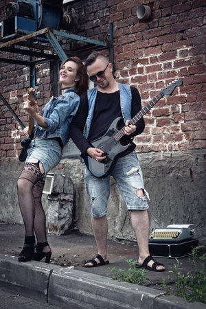 Girl and guy punks on a city street play on guitarsの写真素材