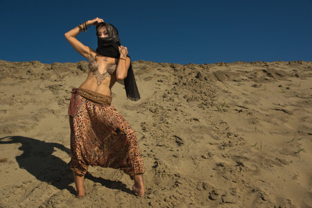 Oriental woman in a sandy desert. Her body is covered with mehendi patternsの写真素材