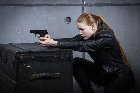 Hit woman. Biker girl in a black suit with gun in handの写真素材