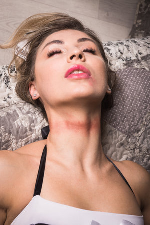 Crime scene imitation. Strangled chambermaid lying on the sofaの写真素材