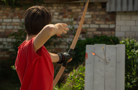 Archery boy bends bow archer target narrow in the summer field