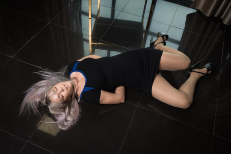 Crime scene simulation: dead girl with hands tied lying on the floor. She was strangled with a rope.の写真素材