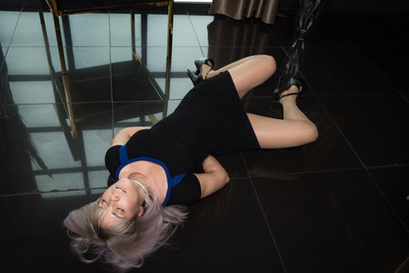 Crime scene simulation: dead girl with hands tied lying on the floor. She was strangled with a rope.の写真素材