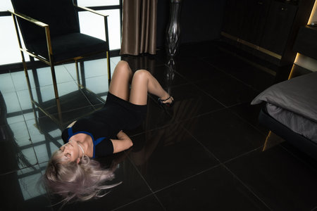 Crime scene simulation: dead girl with hands tied lying on the floor. She was strangled with a rope.の写真素材