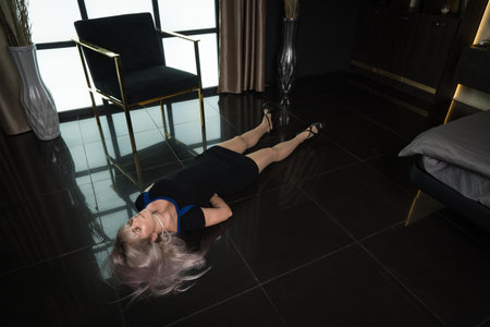 Crime scene simulation: dead girl with hands tied lying on the floor. She was strangled with a rope.の写真素材