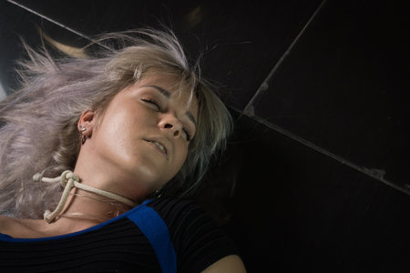 Crime scene simulation: dead girl with hands tied lying on the floor. She was strangled with a rope.の写真素材