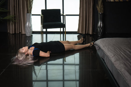 Crime scene simulation: dead girl with hands tied lying on the floor. She was strangled with a rope.の写真素材