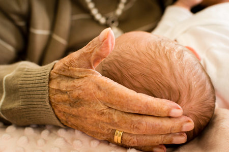 grandmother's hand of rough and old skin caressing the head of her newborn grandchild