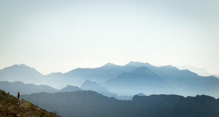 Hiker looking at the Cantabrian mountain range surrounded by haze on a sunny summer morningの写真素材