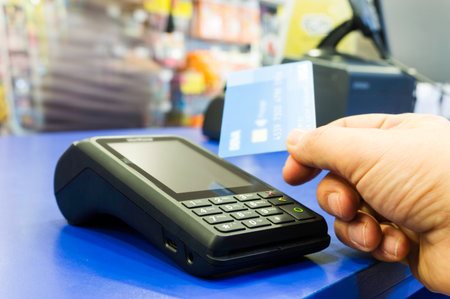 Mobile payments concept. Customer is paying using wireless or contact-less credit card and payment terminal with NFC technologyの写真素材