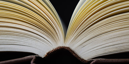 Close-up view of slightly turning book pages in soft warm light with shallow depth of field