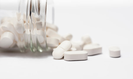 Closeup of a group white pills in crystal bottle on white background close up with copy space.