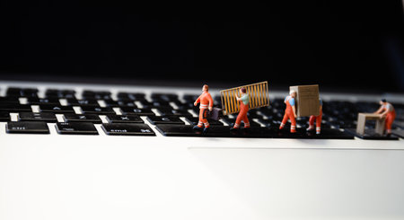 Miniatures of figurines workers moving furniture with keyboard at background.の写真素材